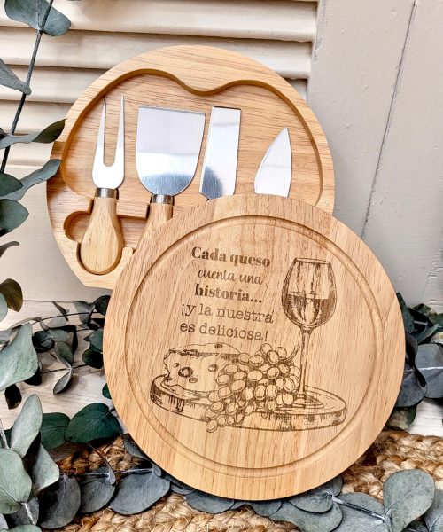 Tabla de quesos madera con grabado de un vaso de vino y utensilios para cortar queso, acompañada de uvas.